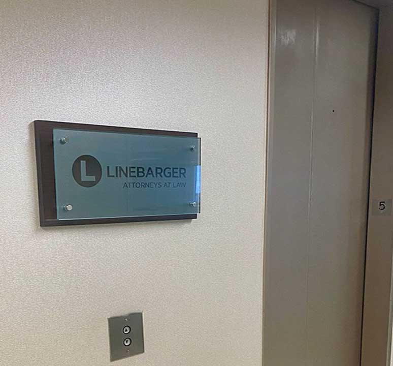 Glass-mounted Linebarger office identification sign beside an elevator