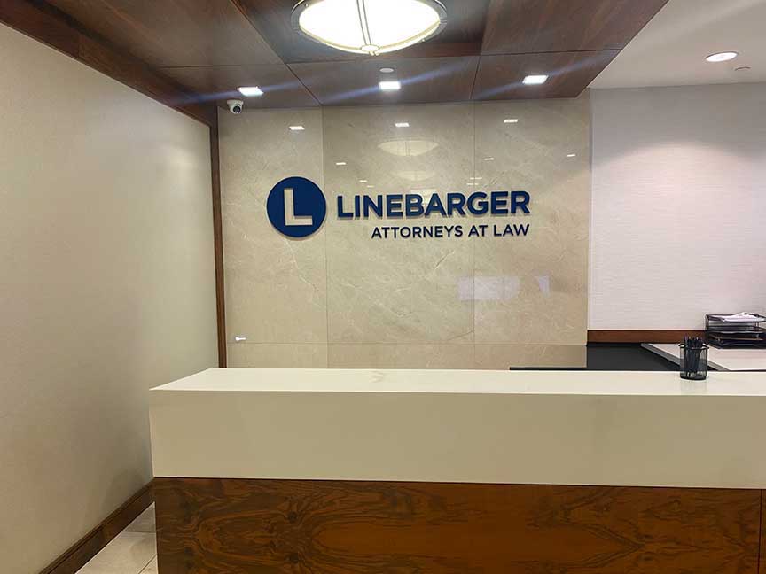Houston dimensional logo lobby sign for Linebarger installed behind a corporate reception desk